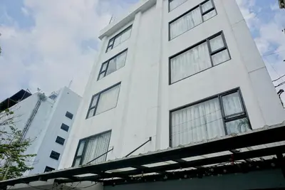 a white building with windows on the side of it at Silom Soi 3 Hash Apartment in Bangkok