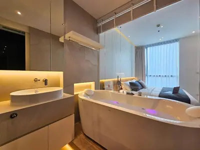 a large bathroom with a tub and a bed in it at The Address 28 in Bangkok