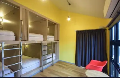 a room with three bunk beds with a red chair at Bangkok Chat box Hostel in Bangkok