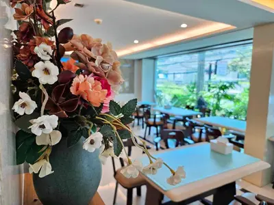 a vase filled with flowers on a table in a restaurant at Sam Homestay in Bangkok