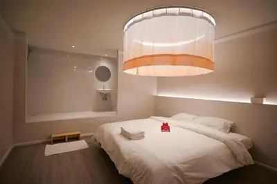 a bedroom with a large white bed with a chandelier at ABC Bangkok RCA in Bangkok