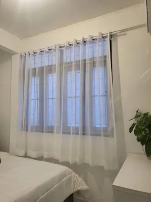 a bedroom with a window with white curtains at Aunty Thong's House in Bangkok