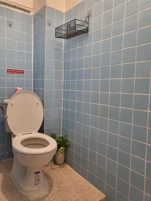 a bathroom with a toilet in a blue tiled wall at Aunty Thong's House in Bangkok