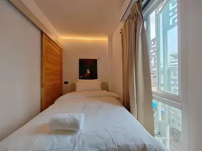 a bedroom with a bed and a large window at The Motuga Hostel Bangkok in Bangkok