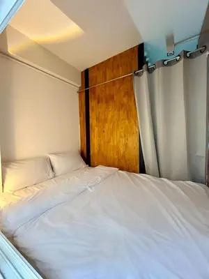 a bed in a small room with a wooden door at The Motuga Hostel Bangkok in Bangkok