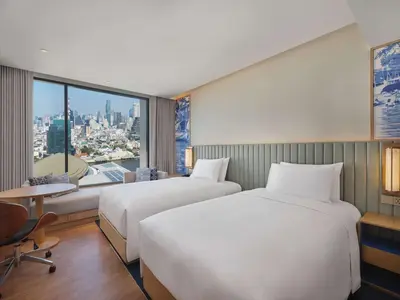 two beds in a hotel room with a large window at Hilton Garden Inn Bangkok Riverside in Bangkok