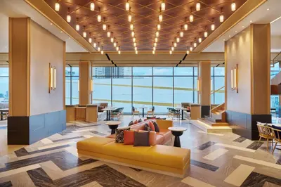 a lobby with a yellow couch in a building at Hilton Garden Inn Bangkok Riverside in Bangkok
