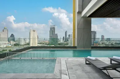 a swimming pool on top of a building with a city skyline at Hilton Garden Inn Bangkok Riverside in Bangkok