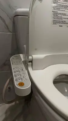 a white toilet with a remote control next to it at Cozy 2BR Duplex-Apartment in Thong Lor in Bangkok