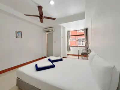 a white bedroom with a large bed with a ceiling fan at V Reserve at Merry V in Bangkok