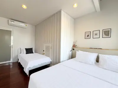 two beds in a bedroom with white walls and wood floors at Vélin - Chinatown in Khlong San