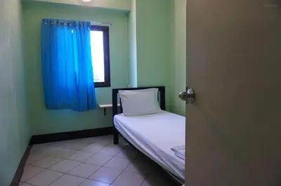 a small room with a bed with a blue curtain at Bella Bella House in Bangkok