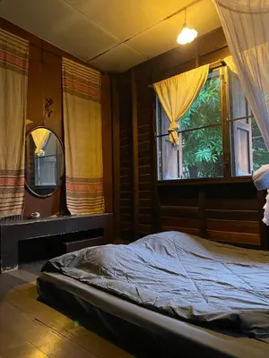 a bedroom with a bed and two windows with curtains at Chest's Place in Bangkok