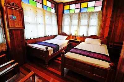 two beds in a room with stained glass windows at Kaloang home in Bangkok