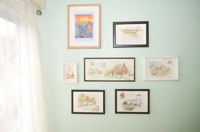 a group of framed pictures on a white wall at Good Day Hostel in Bangkok