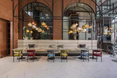 a restaurant with colorful chairs and a table and chandeliers at Cassia Rama 9 Bangkok, part of Banyan Group in Bangkok