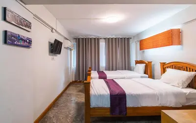 a hotel room with two beds and a tv at XX GO INN Khaosan Road BKK โกอินน์ ตรอกข้าวสาร in Bangkok