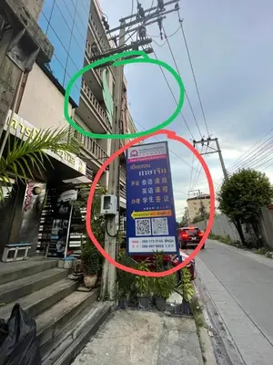 a sign on the side of a building with a green circle at Le Ram Hotel No windows in Bangkok