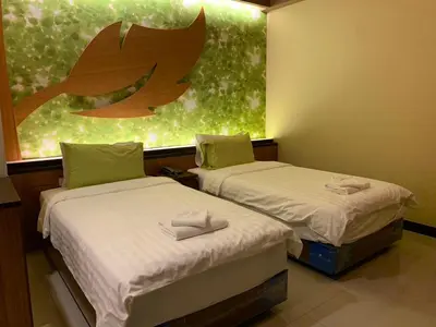 two beds in a room with a painting on the wall at Le Ram Hotel No windows in Bangkok