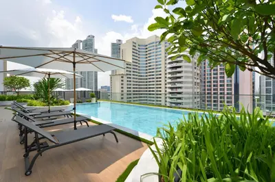 a swimming pool with chairs and an umbrella on a building at GM Estate Hotel and Executive Apartments, Bangkok Sukhumvit 20 in Bangkok