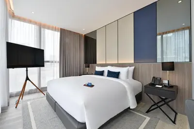 a bedroom with a large white bed and a television at GM Estate Hotel and Executive Apartments, Bangkok Sukhumvit 20 in Bangkok