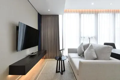 a living room with a white couch and a flat screen tv at GM Estate Hotel and Executive Apartments, Bangkok Sukhumvit 20 in Bangkok