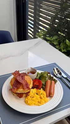 a plate of breakfast food with eggs bacon and vegetables at GM Estate Hotel and Executive Apartments, Bangkok Sukhumvit 20 in Bangkok