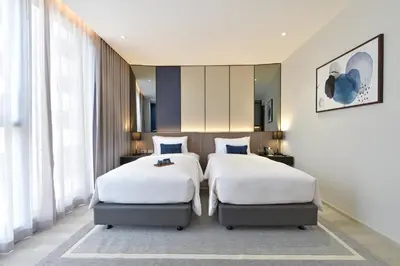 a bedroom with two beds and a mirror at GM Estate Hotel and Executive Apartments, Bangkok Sukhumvit 20 in Bangkok