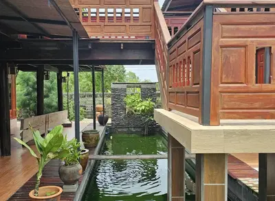a house with a koi pond on a patio at Nipatra Homestay in Ban Khlong Bang Sai