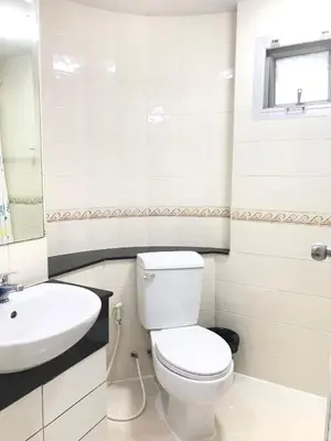 a white bathroom with a toilet and a sink at Charming Resident Sukhumvit 22 in Bangkok