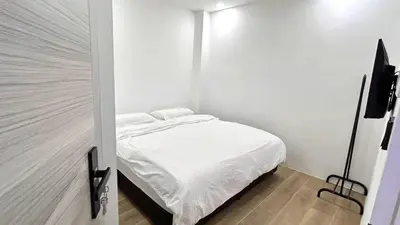 a small bedroom with a bed with white sheets at 65 Hostel Bangkok in Bangkok Noi