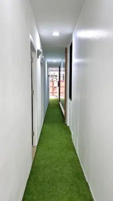 a corridor with green carpet in a white hallway at 65 Hostel Bangkok in Bangkok Noi