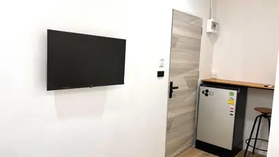 a flat screen tv hanging on a wall next to a refrigerator at 65 Hostel Bangkok in Bangkok Noi