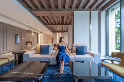 a woman in a blue dress sitting on a couch in a room at Marriott Executive Apartments, Bangkok Townhall Sukhumvit in Bangkok