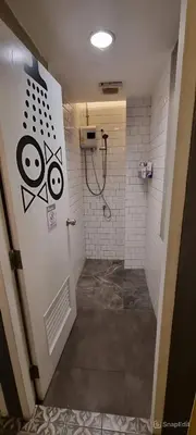 a bathroom with a shower with graffiti on the door at The Space Hometel - Women Only in Pom Prap