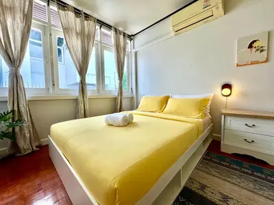 a yellow bed in a room with windows at Flow In House in Bangkok