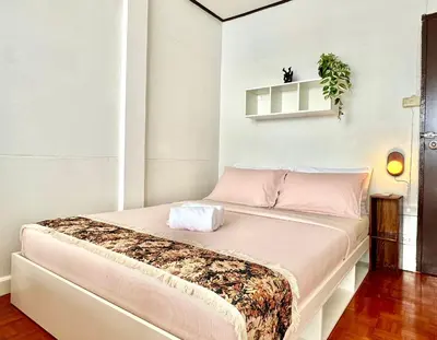 a small bedroom with a bed with pink sheets at Flow In House in Bangkok