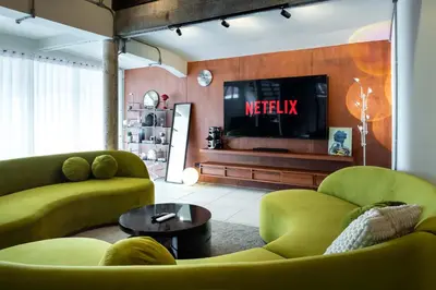 a living room with two green couches and a television at Baan Jila in Bangkok
