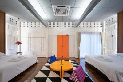 a hotel room with two beds and a table at Baan Jila in Bangkok