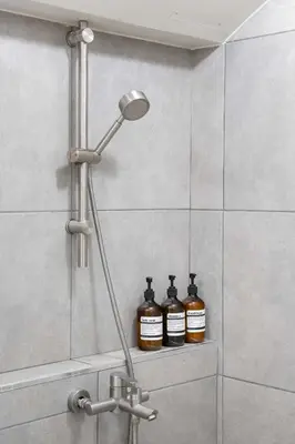 a shower with two bottles on a shelf in a bathroom at Baan Jila in Bangkok