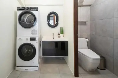 a bathroom with a washer and dryer next to a toilet at Baan Jila in Bangkok