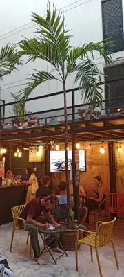 a group of people sitting in a room with a palm tree at AREA81 HIDEOUT Hostel Khaosan in Bangkok