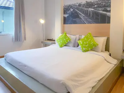 a large white bed with green pillows on it at Anda Ramkhamhaeng By St James Hotel in Bangkok