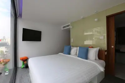 a bedroom with a large white bed and a flat screen tv at S Box Sukhumvit Hotel in Bangkok