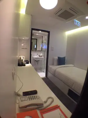 a room with a bed and a desk with a keyboard at S Box Sukhumvit Hotel in Bangkok