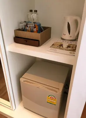 a small refrigerator under a shelf in a room at S Box Sukhumvit Hotel in Bangkok
