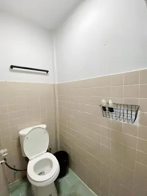 a bathroom with a toilet and a tiled wall at GO INN Siriraj - โกอินน์ ศิริราช Pro in Bangkok Noi