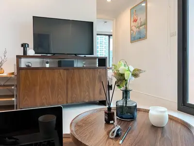 a living room with a table with a television on a cabinet at Expansive Luxury 2BR - Ultra Fast Wifi - Phrom Phong in Bangkok