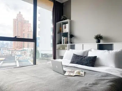a bedroom with a laptop on a bed with a window at Stylish Riverview 1BR - Ultra Fast WiFi - Phrom Phong in Bangkok