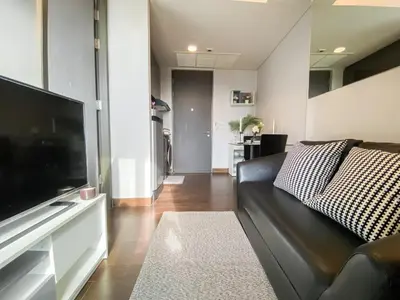 a living room with a couch and a flat screen tv at Stylish Riverview 1BR - Ultra Fast WiFi - Phrom Phong in Bangkok